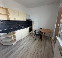 A kitchen in a 2-room apartment with a wooden decor floor and a dining area.