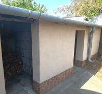 The side part of a family house in Nové Zámky with a wood storage and water drainage.