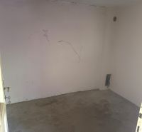 An empty room with cracked walls in a family house, suitable for renovation.