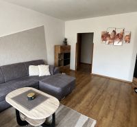Living room in a three-room apartment with a corner sofa and a wooden decor floor.