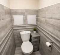 A bathroom with wood-patterned tiles and sanitary ware in a 3-room apartment.