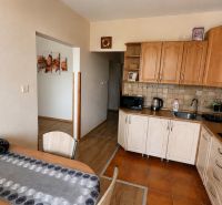 A kitchen in a 3-room apartment with wooden decor on the floor and wooden cabinets.