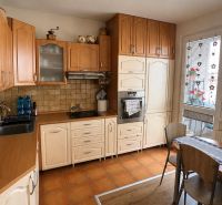 A kitchen in a 3-room apartment with light furniture and a wooden decor floor.