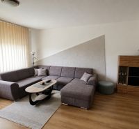 Living room with a corner sofa, table, and wooden decor flooring in a 3-room apartment.
