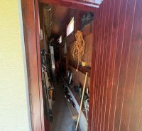 A narrow storage room in a cabin with tools and a small window.