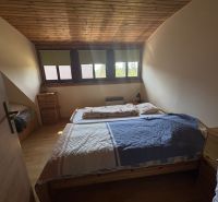 A bedroom with a wooden ceiling and a wood-patterned floor in a cabin.