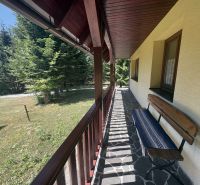 At the Chata na Donovaloch, you can see a stone terrace with a bench and surrounding trees.
