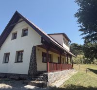 A cottage in Donovaly with a slanted roof and stone details on a sunny meadow.