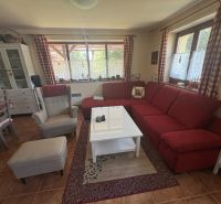 Living room in a cabin with a red sofa, armchair, and dining table.