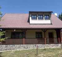A cottage in Donovaly with a stone base and wooden railing on the porch.