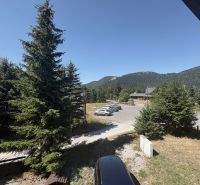 A cottage in Donovaly with a view of the mountains and parking in front of the building.