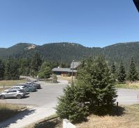 A picturesque view of a cottage in Donovaly surrounded by mountain nature and a parking lot.