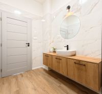 A bathroom with a sink on a wooden decor and a mirror in a 4-room apartment.