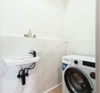 Bathroom with a sink and a washing machine in a 4-room apartment, floor with wood decor.