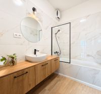 A bathroom in a 4-room apartment with a marble wall and a wooden decor floor.
