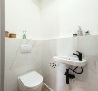 Bathroom with wall-mounted toilet, sink, and floor with wood decor in a 4-room apartment.