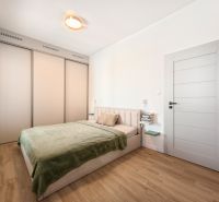 A bedroom with a bed, built-in wardrobe, and wooden decor flooring in a 4-room apartment.