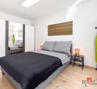 Bedroom with a bed and a mirrored wardrobe in a studio apartment, floor with wood decor.