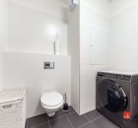 A bathroom in a studio apartment with a washing machine and a wall-mounted toilet.