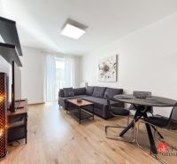Living room with a dark gray sofa, dining table, and wood-patterned flooring.