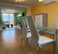 Dining room in a 3-room apartment with a wooden decor floor and a view of the living area.