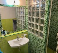 Bathroom in a 3-room apartment with a sink and green mosaic tiles.