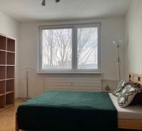 A bedroom with a light wall, a bed, and a floor with a wooden decor in a 3-room apartment.