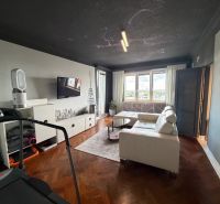 A stylishly furnished living room with a white sofa and a wooden decor floor.