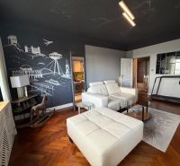 Living room with a sofa, tapestry, treadmill, and wooden decor flooring in a 4-room apartment.