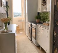 A kitchen in a 4-room apartment with white cabinets and a wood-patterned floor.