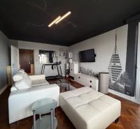 Living room with a white sofa, television, and wood-patterned flooring in a four-room apartment.