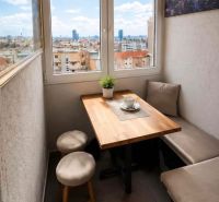 Cozy dining nook in a 4-room apartment with a view of the city and wall decoration.