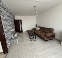 Living room with a brown sofa, wood-patterned flooring, and patterned wallpaper.