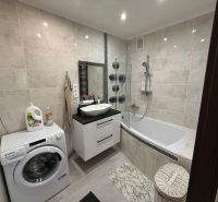 Bathroom with a bathtub, washing machine, and sink in a 3-room apartment.