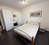A bedroom with a wood-decor floor in a 3-room apartment, equipped with a wardrobe and a bed.