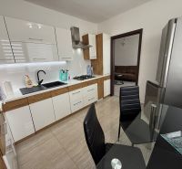 A kitchen with a modern cabinet, black sink, and glass table in a three-room apartment.