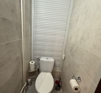 Bathroom with toilet and blinds in a 3-room apartment, beige tiles and accessories.