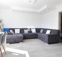 Living room in a 3-room apartment with a sofa, dining area, and wooden decor flooring.