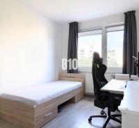 A room in a 3-room apartment with a bed, a computer desk, and a floor with a wooden decor.