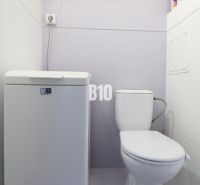 A bathroom in a 3-room apartment with a toilet and a top-loading washing machine.
