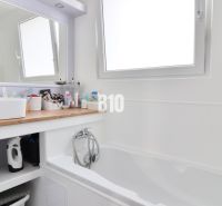 A bathroom in a 3-room apartment with a bathtub, sink, and storage space.