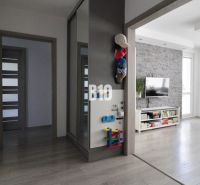 Interior of a 3-room apartment with wood-patterned flooring, a living room wall unit, and a dining table.