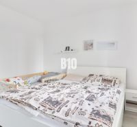 A bright bedroom with a simple bed in a three-room apartment, wooden floor decor.