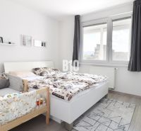 Bedroom in a 3-room apartment with a bed, a baby crib, and a floor with a wooden decor.