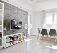 Living room in a 3-room apartment with brick cladding and a wooden decor floor.