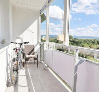 The balcony of a 3-room apartment in Martin with a view of greenery and buildings.