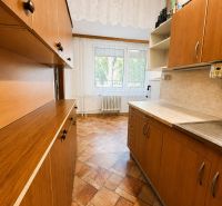 A kitchen in a 3-room apartment with a wooden decor floor and curtains.