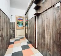 A hallway in a 3-room apartment with colorful tiles and wooden decor on the walls.