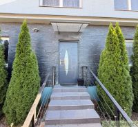 The entrance to a family house in Komárno with elegant stairs and thuja trees around.
