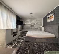 The bedroom with a bed in the family house has a stylish wallpaper and a TV on the wall.